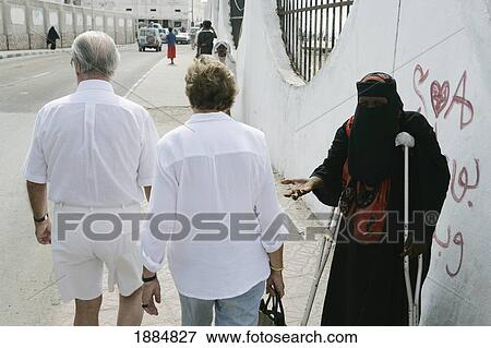 Elderly Tourists Ignoring A Crippled Woman Begging As They Pass View Large Photo Image Stock Photo - Elderly Tourists Ignoring A Crippled Woman Begging As They Pass. Fotosearch