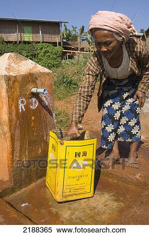 Stock Photography - Elderly Woman Collecting Water From The Communal Pump, Myanmar / Burma. Fotosearch