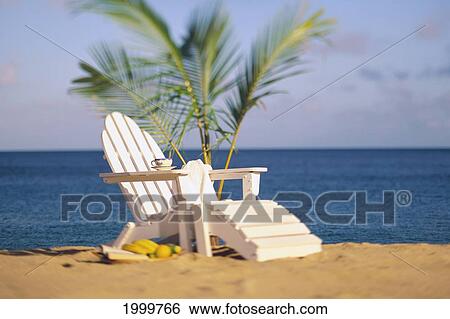 Stock Photograph - Empty White Beach Chair With Towel And Coffee Cup, Small Palm Tree, Blue Ocean. Fotosearch