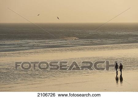 Stock Photograph - England, East Sussex, Couple strolling on beach; Hastings. Fotosearch