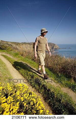 Stock Image - England, Guernsey, Tourist on beach path; Torteval. Fotosearch
