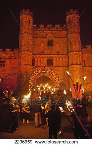 Stock Photo - England, People with burning torches going through archway to Battle Abbeyt; East Sussex. Fotosearch