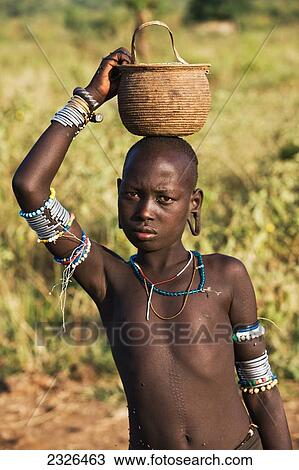 Ethiopia, Omo Valley, Southern Mursiland, Portrait of Young Mursi boy carrying container of sorghum; Dirikoro View Large Photo Image Stock Image - Ethiopia, Omo Valley, Southern Mursiland, Portrait of Young Mursi boy carrying container of sorghum; Dirikoro. Fotosearch