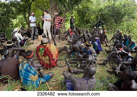 Stock Image - Ethiopia, South Western Ethiopia, Omo Valley, Southern Mursiland, View of archaeologist with Mursi people; Dirikoro. Fotosearch