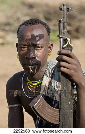 Stock Image - Ethiopia, Southern Nations Nationalities And Peoples' Region, South Omo, Mursiland, Portrait Of Mursi Tribal Man With Gun; Maridungka Village. Fotosearch