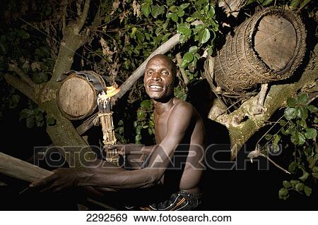 Ethiopia, Southern Nations Nationalities And Peoples' Region, South Omo, Mursiland, Portrait Of Mursi Tribal Man Smoking Beehive High Up In Tree At Night To Collecting Honey; Makki Village View Large Photo Image Stock Photo - Ethiopia, Southern Nations Nationalities And Peoples' Region, South Omo, Mursiland, Portrait Of Mursi Tribal Man Smoking Beehive High Up In Tree At Night To Collecting Honey; Makki Village. Fotosearch