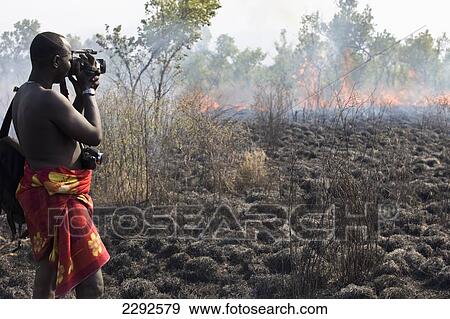 Ethiopia, Southern Nations Nationalities And Peoples' Region, South Omo, Side View Of Mursi Tribal Man Filming Controlled Fire On Savanah; Southern Mursiland View Large Photo Image Stock Photo - Ethiopia, Southern Nations Nationalities And Peoples' Region, South Omo, Side View Of Mursi Tribal Man Filming Controlled Fire On Savanah; Southern Mursiland. Fotosearch