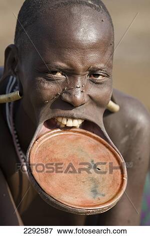 Ethiopia, Southern Nations Nationalities And Peoples' Region, South Omo, Southern Mursiland, Portrait Of Mursi Tribal Woman With Large Pottery Lip-Plate (Dhebi); Mirobe Village View Large Photo Image Stock Photo - Ethiopia, Southern Nations Nationalities And Peoples' Region, South Omo, Southern Mursiland, Portrait Of Mursi Tribal Woman With Large Pottery Lip-Plate (Dhebi); Mirobe Village. Fotosearch