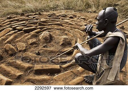 Ethiopia, Southern Nations Nationalities And Peoples' Region, South Omo, Southern Mursiland, Mursi Tribesman Next To Benna Kulugto Stone Platforms; Dirikoro View Large Photo Image Stock Photo - Ethiopia, Southern Nations Nationalities And Peoples' Region, South Omo, Southern Mursiland, Mursi Tribesman Next To Benna Kulugto Stone Platforms; Dirikoro. Fotosearch