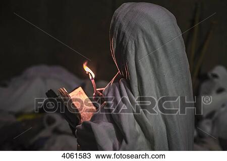 Stock Image - Ethiopian pilgrim with Bible and candle; Lalibela, Ethiopia. Fotosearch