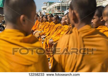 Stock Image - Every morning young monks go around the city blessing every shop or restaurant; Battambang, Cambodia. Fotosearch