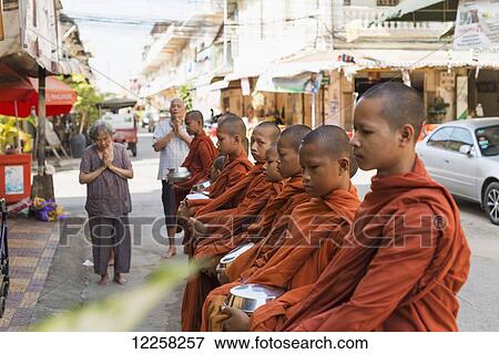 Stock Photo - Every morning young monks go around the city blessing every shop or restaurant; Battambang, Cambodia. Fotosearch