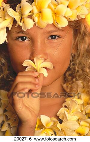 Stock Photograph - Extreme Close-Up Of Young Girl Holding Plumeria Flower To Nose, Smelling. Fotosearch