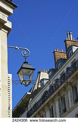 Stock Photograph - Facade and chimneys on a residential building with a light in Marais district; Paris, France. Fotosearch