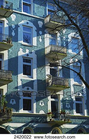 Stock Image - Facade of a residential building with ornate white window trim and small balconies; Hamburg, Germany. Fotosearch