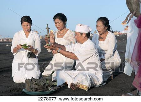 Family and priest making an offering at the Melasti Festival to honor the gods of the sea; Bali, Indonesia View Large Photo Image Stock Photo - Family and priest making an offering at the Melasti Festival to honor the gods of the sea; Bali, Indonesia. Fotosearch
