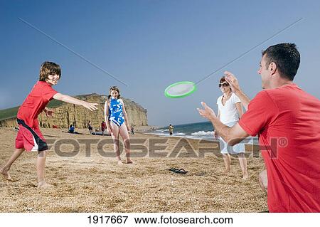 Stock Photo - Family Playing With Frisbee On Beach. Fotosearch