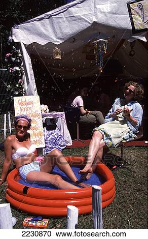 Stock Image - Family Sunbathing In Garden With Inflatable Pool, Somerset, Uk.. Fotosearch