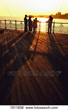 Family Watching Sunset Over City And Ocean From Brighton Pier, Brighton, Uk View Large Photo Image Stock Photo - Family Watching Sunset Over City And Ocean From Brighton Pier, Brighton, Uk. Fotosearch