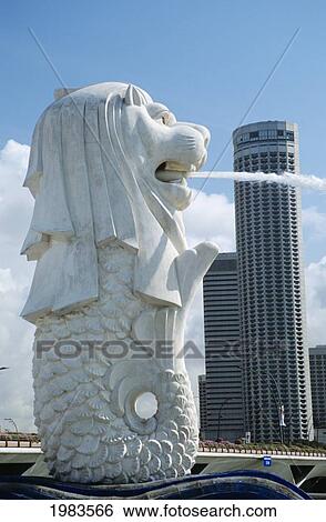 Stock Photograph - Famous Merlion Fountain with tall buildings in background; Singapore. Fotosearch