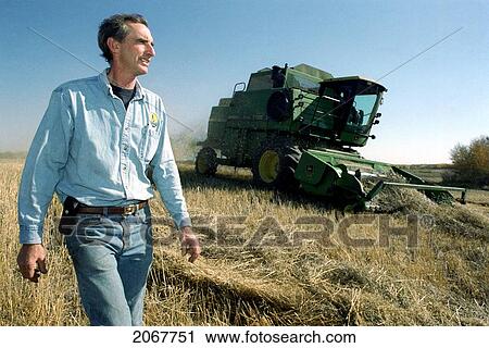Stock Image - Farmer In Field With Machinery In Background, Minnedosa, Manitoba. Fotosearch