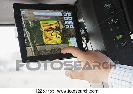 Stock Photography - Farmer uses technology in tractor for soybean harvesting; Minnesota, United States of America. Fotosearch