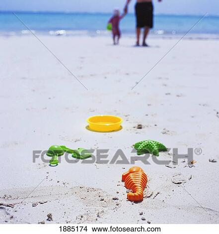 Picture - Father And Daughter Walking On The Beach, Plastic Toys In Foreground. Fotosearch