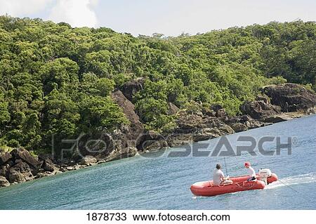 Stock Image - Father And Son Fishing In Boat Off Lush Coastline. Fotosearch