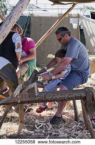 Stock Photo - Father and son learning traditional woodworking, music festival; Dorset, England. Fotosearch