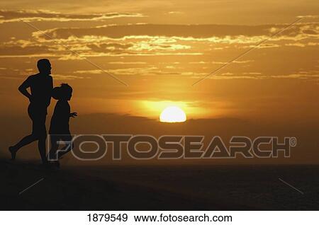 Stock Photo - Father And Son Running On Sand Dunes At Sunset. Fotosearch