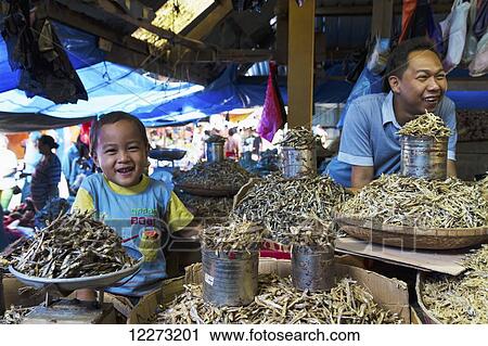 Stock Image - Father and son selling dried fish at the Bolu market, Makassar (Ujung Pandang), South Sulawesi, Indonesia. Fotosearch