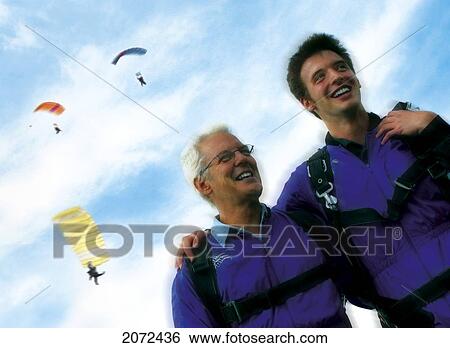 Stock Photograph - Father And Son Smiling, Three Parachutists Flying In Sky Background. Fotosearch