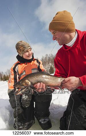 Stock Photo - Father and son with a large winter brook trout caught while ice fishing; Ontario, Canada. Fotosearch