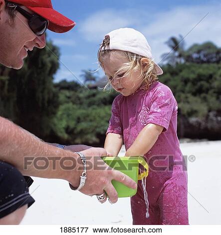Stock Photo - Father Holding Bucket For Daughter Playing On The Beach. Fotosearch