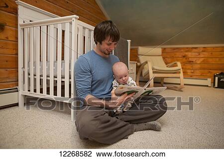 Father holding his child and reading a bedtime story while sitting on the floor in the nursery, USA View Large Photo Image Stock Image - Father holding his child and reading a bedtime story while sitting on the floor in the nursery, USA. Fotosearch