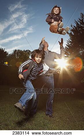 Father tossing one of his sons in the air; Montreal, Quebec, Canada View Large Photo Image Picture - Father tossing one of his sons in the air; Montreal, Quebec, Canada. Fotosearch