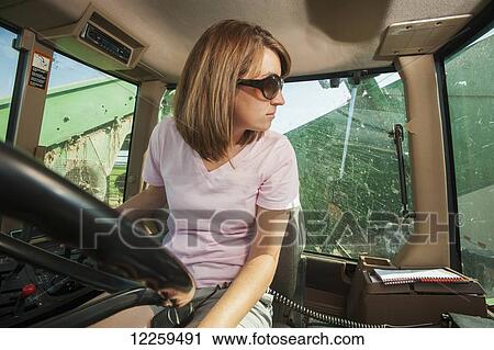 Stock Image - Female farmer in cab, harvesting cucumbers; Preston, Maryland, United States of America. Fotosearch