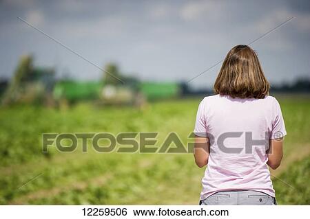 Stock Photograph - Female farmer looking out at her farmland; Preston, Maryland, United States of America. Fotosearch