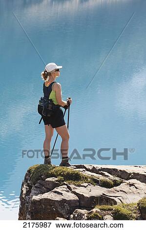 Stock Photo - Female Hiker On Rock Cliff Overlooking Mountain Lake; Field British Columbia Canada. Fotosearch