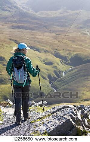 Female hiker on rock trail overlooking grassy river valley below; Letterfrack, County Galway, Ireland View Large Photo Image Stock Image - Female hiker on rock trail overlooking grassy river valley below; Letterfrack, County Galway, Ireland. Fotosearch