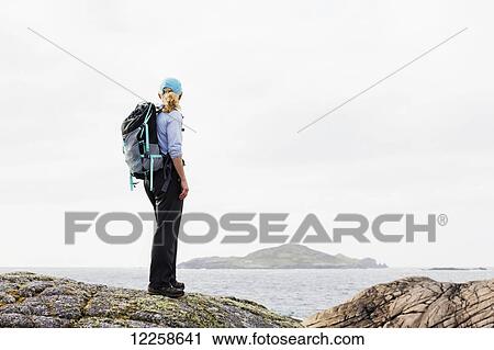 Female hiker on rounded rocks overlooks ocean and island in the distance; Omey Island, County Galway, Ireland View Large Photo Image Stock Image - Female hiker on rounded rocks overlooks ocean and island in the distance; Omey Island, County Galway, Ireland. Fotosearch