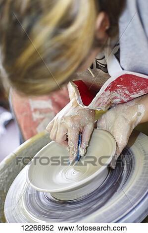 Stock Image - Female sculpting on pottery wheel; Ontario, Canada. Fotosearch