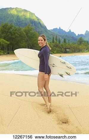 Stock Photograph - Female surfer on the beach; Kauai, Hawaii, United States of America. Fotosearch