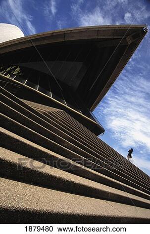 Stock Image - Female Tourist On Steps Of Sydney Opera House, Low Angle View. Fotosearch