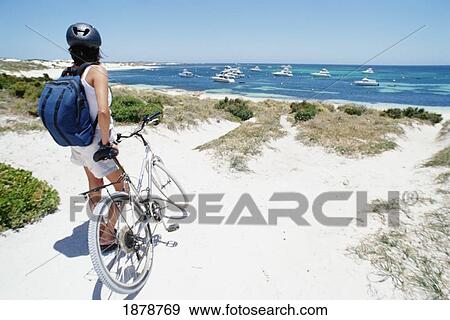 Stock Photo - Female Tourist Standing With Bicycle On The Beach. Fotosearch