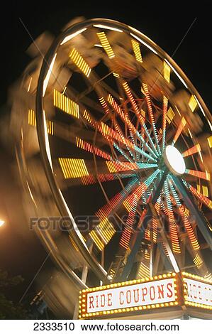 Stock Image - Ferris wheel illuminated in colourful lights at night; Honolulu, Oahu, Hawaii, United States of America. Fotosearch
