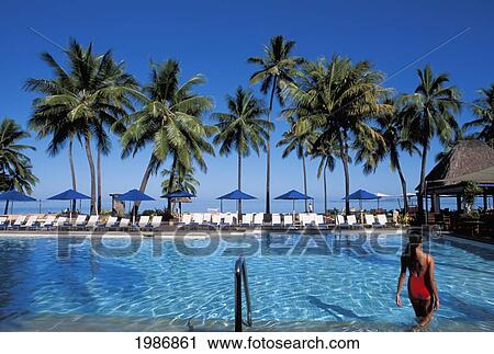 Stock Image - Fiji, Coral Coast, Shangri-La Resort, Woman Wading In Pool, Palms And Blue Sky.. Fotosearch
