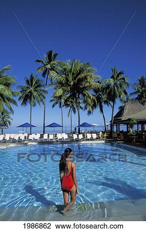 Stock Image - Fiji, Coral Coast, Shangri-La Resort, Woman Wading In Pool, Palms And Blue Sky.. Fotosearch