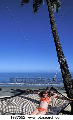Stock Image - Fiji, Coral Coast, Smiling Young Girl Relaxing In Hammock On Beautiful Beach.. Fotosearch
