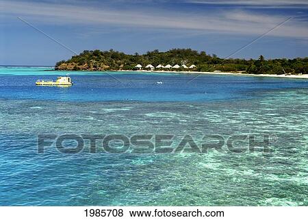 Stock Photo - Fiji, Mamanuca Islands, Mana Island, Yellow Semi Submersible Vessel In Lagoon, Bures Line The Shore, View From Ocean.. Fotosearch